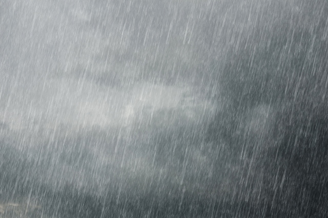 Extremely heavy rain falling at a slight angle with dark, stormy black-and-gray clouds filling the background.