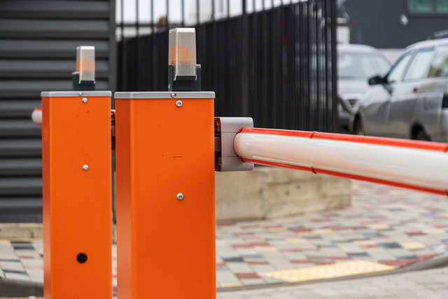 A close-up of a bright orange automatic barrier controls access to the parking lot to improve parking safety.